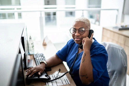 medical assistant answering phone while typing on computer